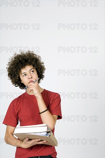 Mixed race student thinking with stack of books