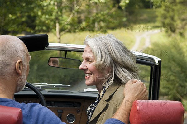 Rear view of older couple driving convertible