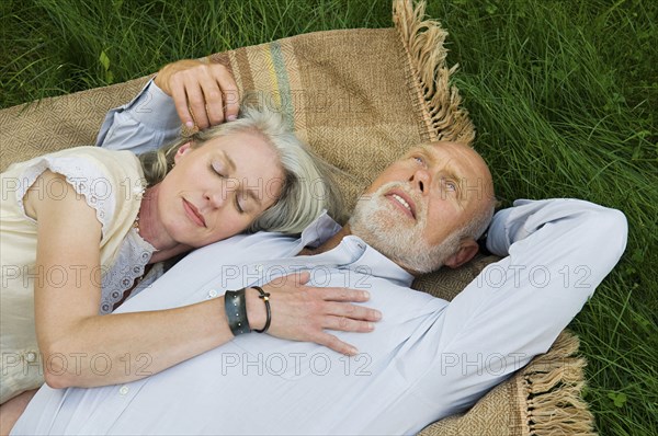 Older couple napping on picnic blanket