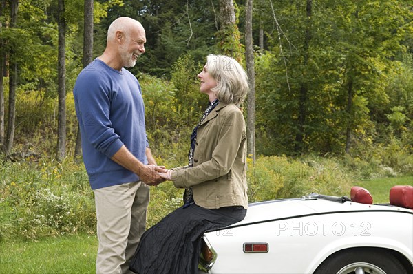 Older couple holding hands on convertible