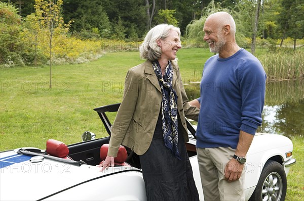 Older couple standing by convertible