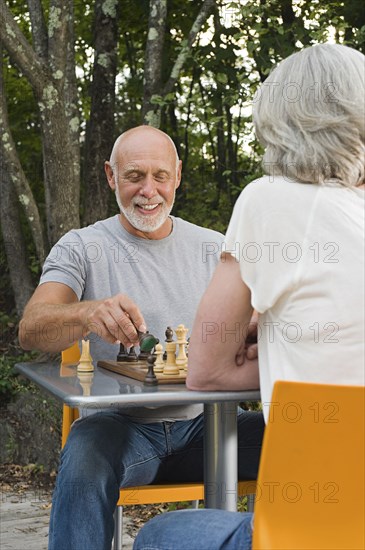 Older couple playing chess in backyard