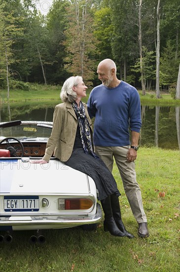 Older couple sitting on convertible in park