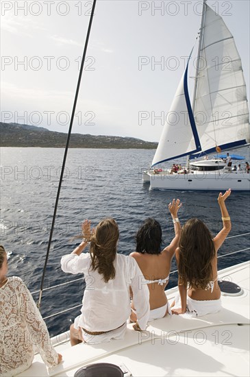 Women waving from sailboat on ocean