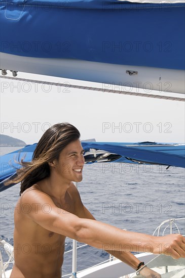 Smiling man standing on sailboat deck