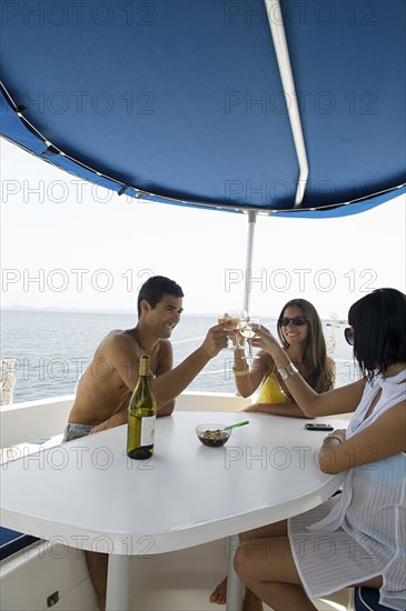 Friends toasting with white wine on sailboat deck