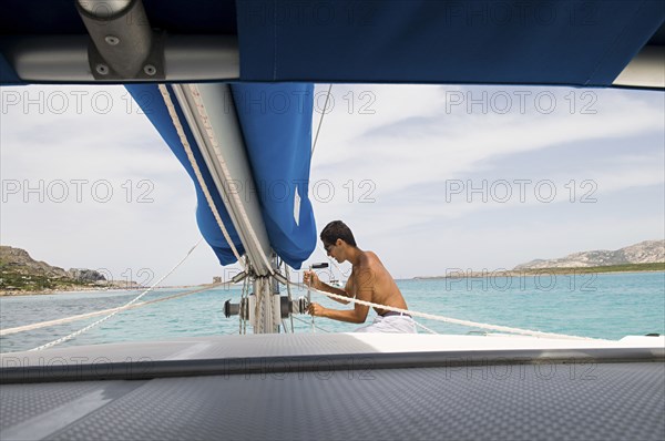 Man hoisting sailboat rigging on deck