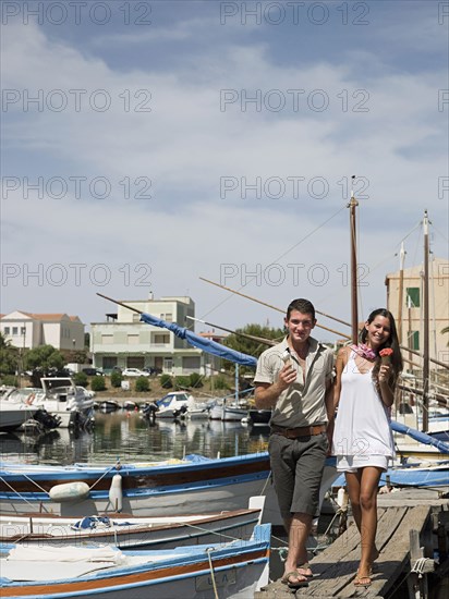 Couple walking on wooden dock in urban harbor