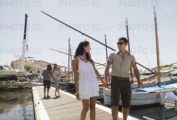 Couple walking on wooden dock in urban harbor