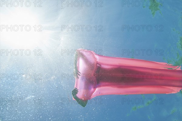 Underwater view of woman sunbathing on raft in ocean