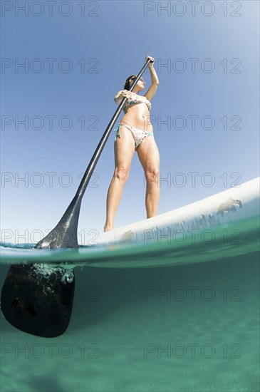 Low angle view of woman standing on paddle board