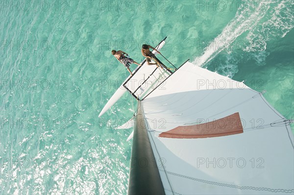 High angle view of men hoisting rigging on sailboat