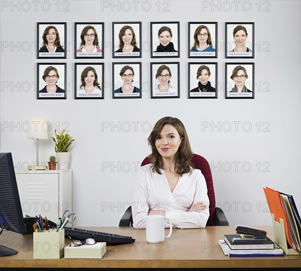 Businesswoman smiling under award pictures in office