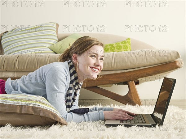 Caucasian woman using laptop on carpet