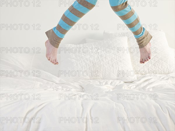 Caucasian woman jumping on bed
