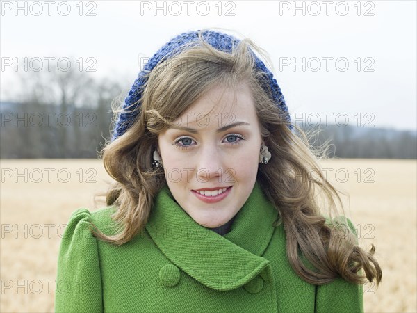 Caucasian woman wearing coat and hat in field