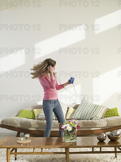 Caucasian woman dancing to headphones in living room