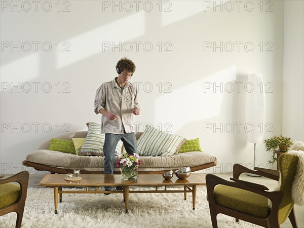 Mixed race man listening to headphones in living room