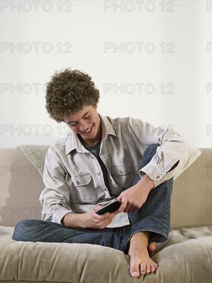 Mixed race man using cell phone on sofa