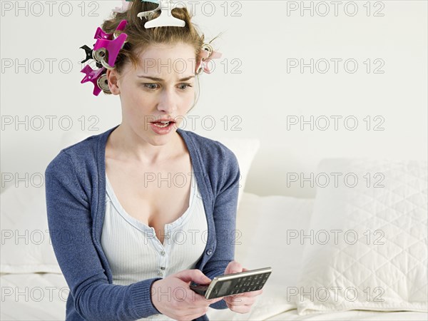 Surprised Caucasian woman using cell phone on sofa