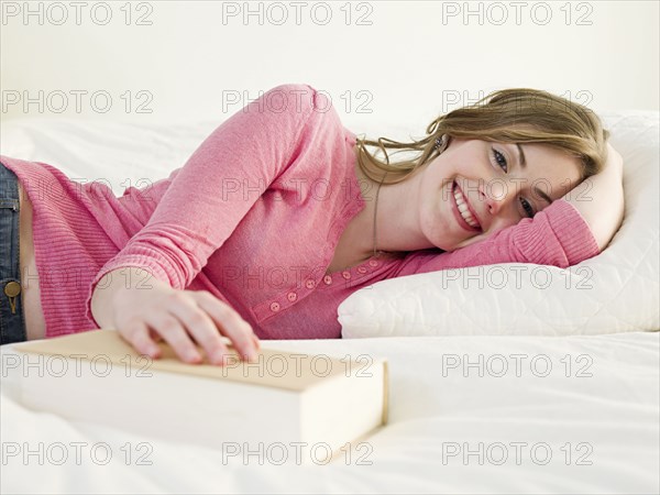 Caucasian woman with book laying on bed
