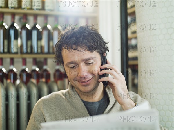 Caucasian man talking on cell phone in restaurant