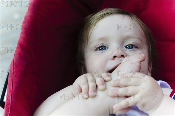 Caucasian baby boy chewing his toes