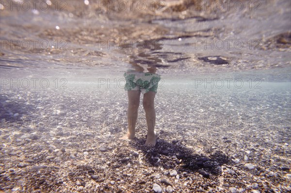 Underwater view of Caucasian girl standing in ocean