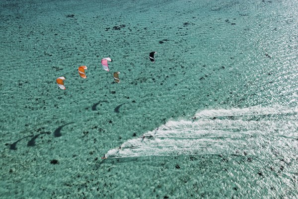 Aerial view of people kitesurfing on ocean
