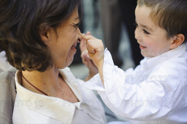 Caucasian boy touching nose of mother