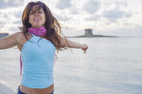 Caucasian woman cheering on beach with arms outstretched