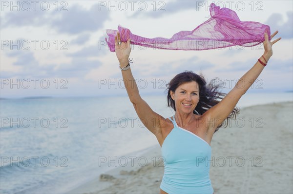 Caucasian woman playing with scarf on beach