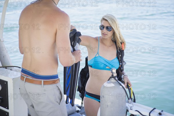 Caucasian divers holding flippers on boat