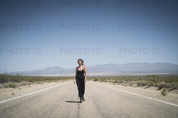 Caucasian woman walking on remote desert road