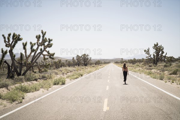 Caucasian woman walking on remote desert road