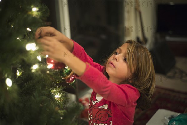 Caucasian boy hanging ornament on Christmas tree