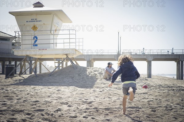 Caucasian boy running to father on beach