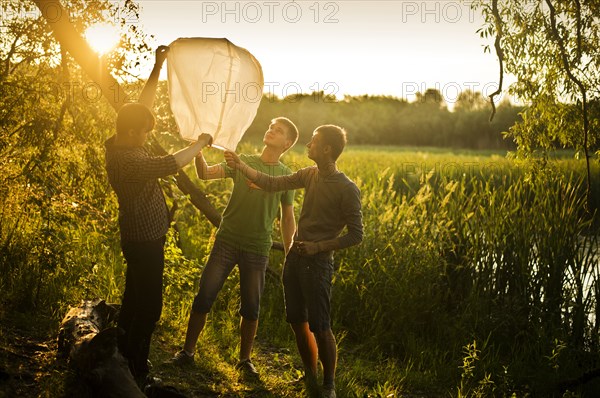 Caucasian men launching floating lantern outdoors