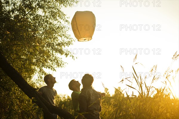 Caucasian men launching floating lantern outdoors