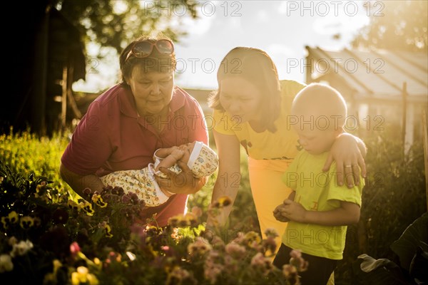 Caucasian family examining flowers in garden