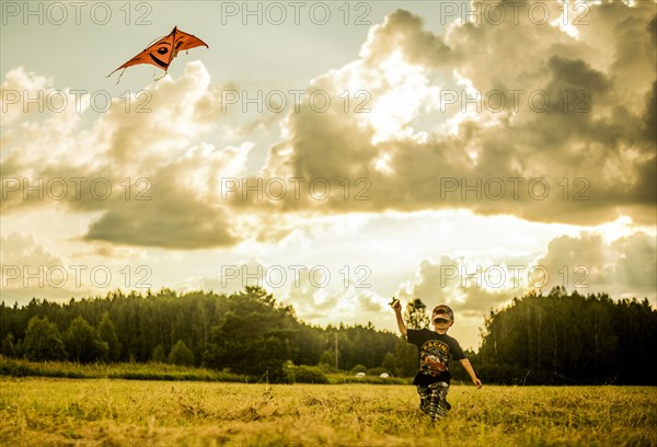 Caucasian boy flying kite in rural field