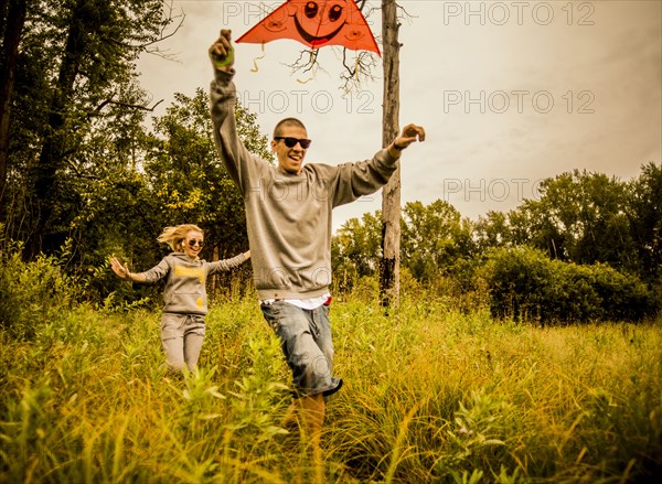 Caucasian couple flying kite in rural field