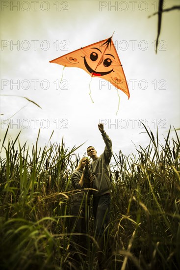 Caucasian couple flying kite in rural field