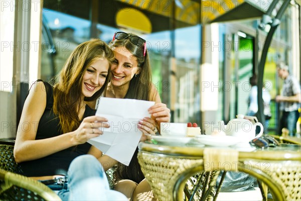 Women reading map together at sidewalk cafe