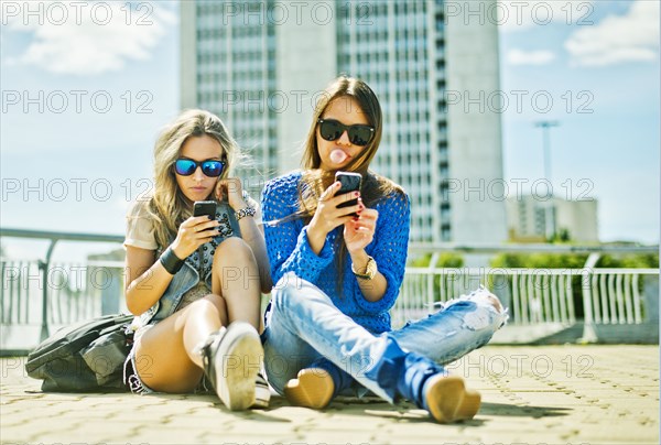 Women using cell phones on city street