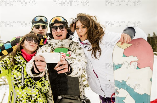 Caucasian friends with snowboard taking selfie