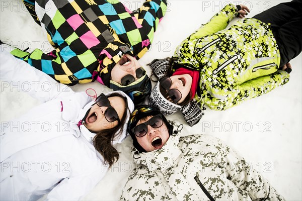 Caucasian friends laying in snow