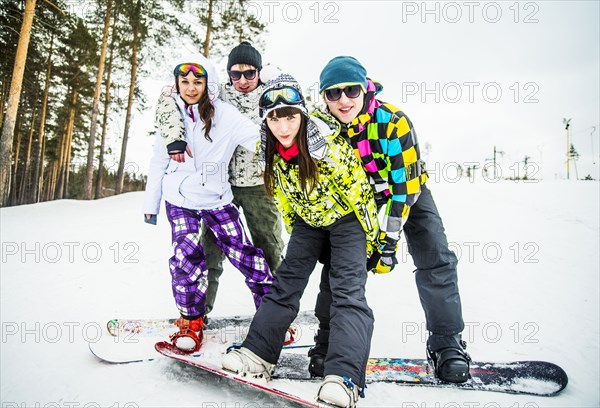 Caucasian couples snowboarding posing on snowy slope