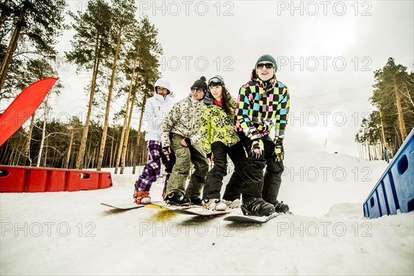 Caucasian couples snowboarding together on snowy hill