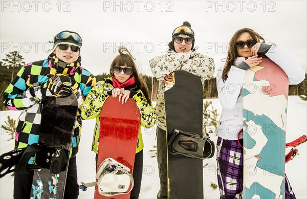 Caucasian couples holding snowboards in snow